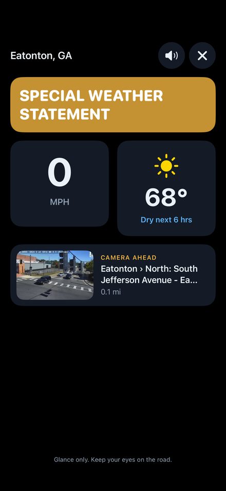 Drive mode showing a large Special Weather Statement banner, speed, temperature and the camera ahead.